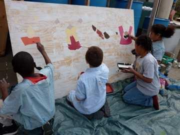 Sustainability Academy second and third graders paint a mural to celebrate diversity during the school s First Annual Day of Service.