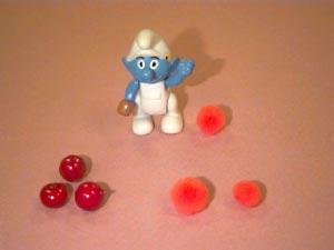 The Smurf is standing by the orange he bought and he his facing the apples and the two oranges that he didn t buy, Picture 5.