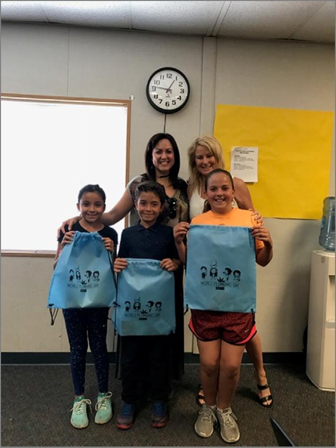 IAPMO Group s Gaby Davis (left) presenting students in Mrs. Parson s class with prizes for the winning posters.