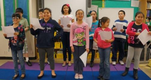 Fifth graders stand proudly before rehearsing their original song.