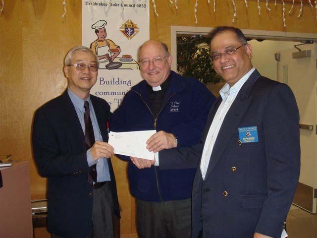 Knights in Action District Deputy Stan Leong presents Monsignor Dennis Luterbach