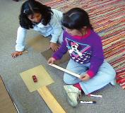Students placed the different surfaces the hand board and three grades of sandpaper at the end of the ramp and measured the distance the car traveled on each surface.