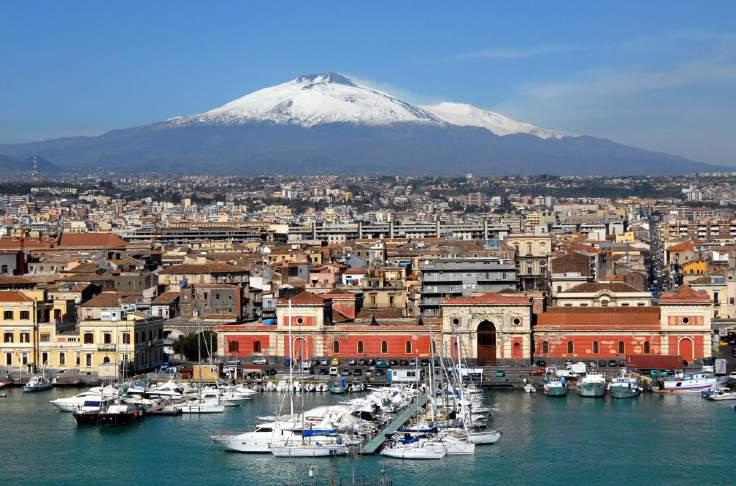 ENJOYING CATANIA LIFE Nestled at the foot of breathtaking Mount Etna, Catania is situated on the stunning east coast of Sicily and faces the beautiful turquoise waters of the Ionian Sea.