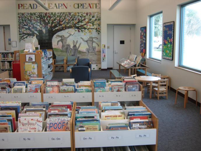 Due to lack of overall space, the children s area is primarily filled with shelving, plus a few cramped tables and chairs.